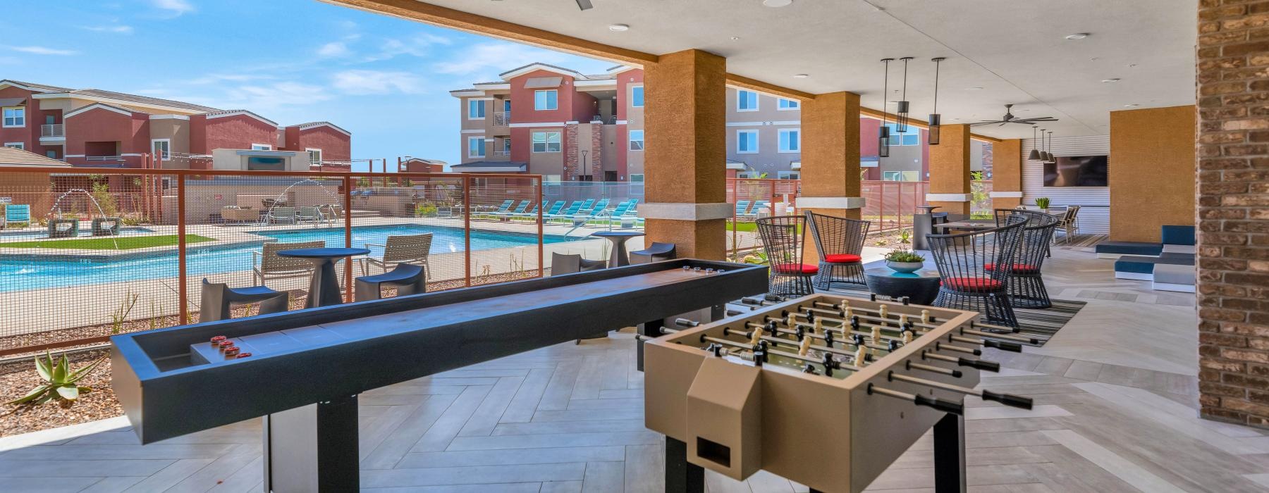 a pool table and chairs in a clubhouse room with a brick wall and a large window