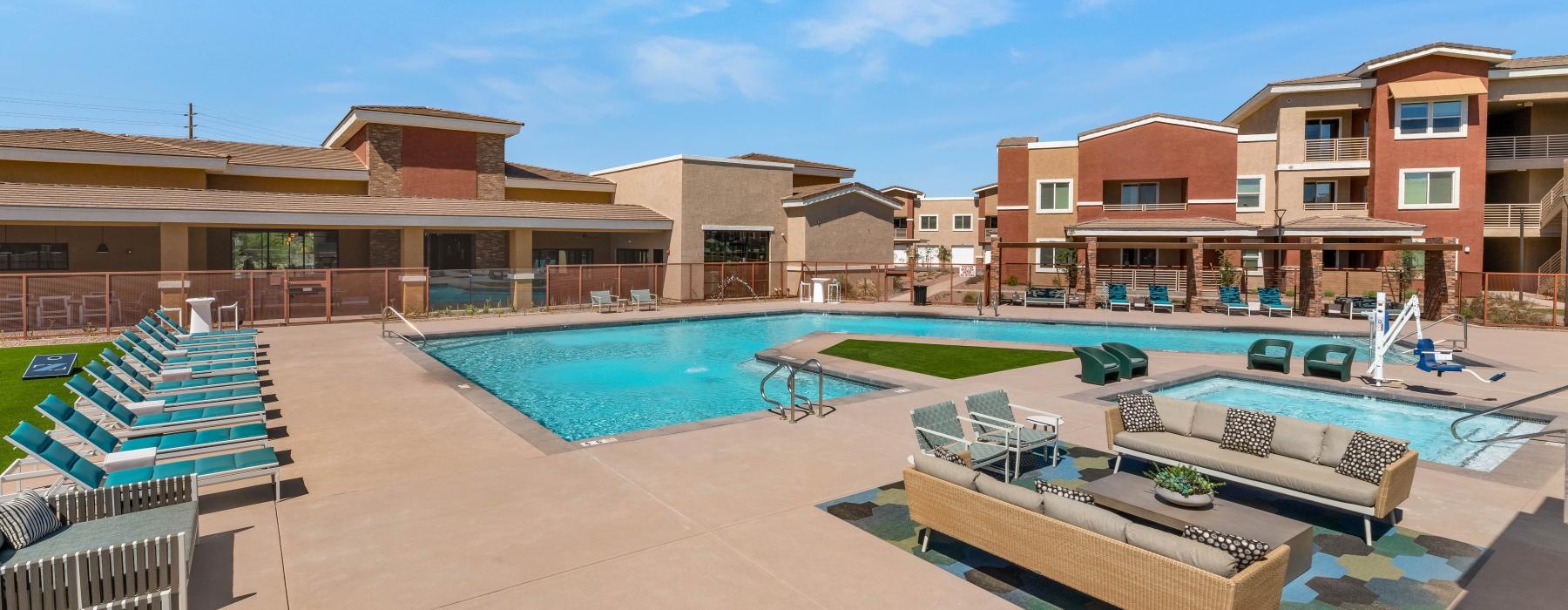 a swimming pool with chairs and a building behind it