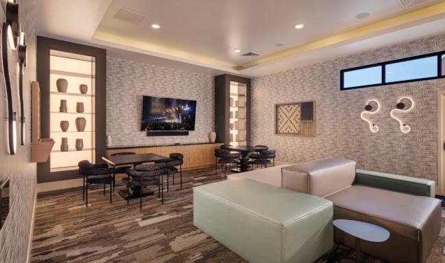 Resident lounge with seating areas and large TV in the clubhouse at Zaterra apartment in Chandler, AZ.